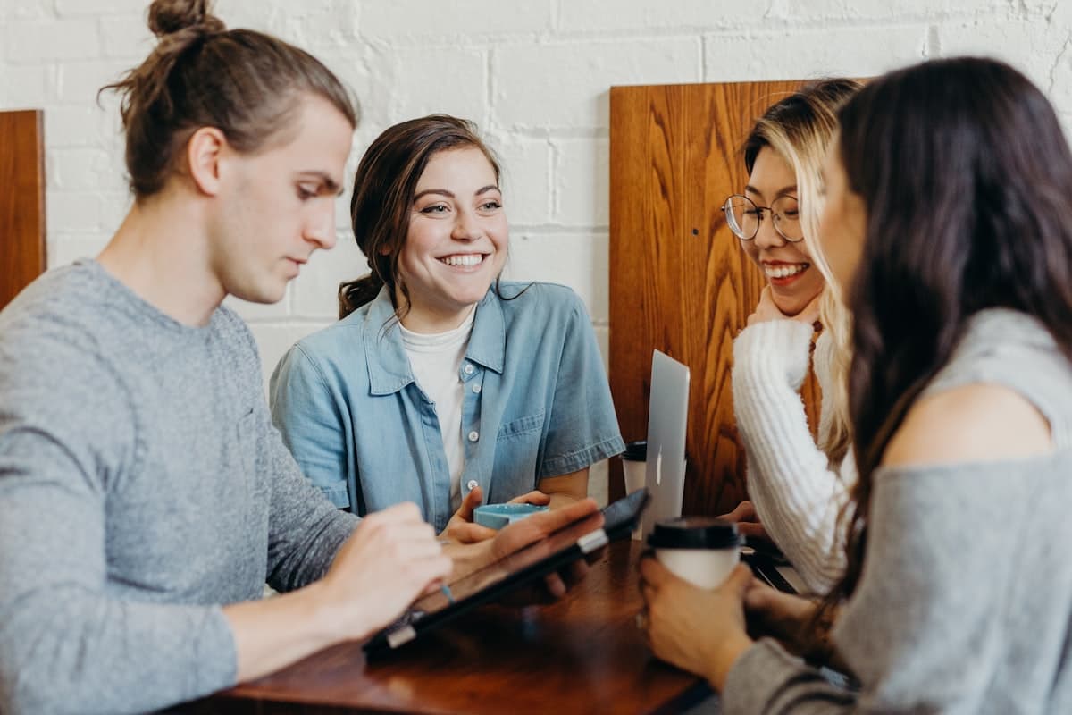A small group of adults in easy conversation around a wooden table